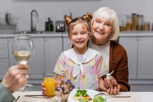 Happy senior woman with granddaughter looking at camera while celebrating easter at home — Stock Photo