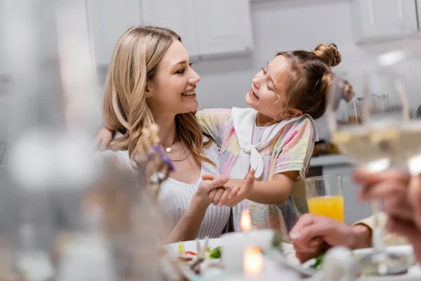 Cheerful mother and daughter holding hands and looking at each other during easter celebration — Stock Photo