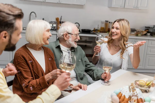 Femme gaie avec verre de vin pointant avec la main pendant le dîner de Pâques en famille — Photo de stock