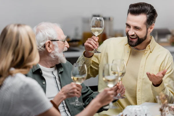Hombre mayor sosteniendo una copa de vino mientras celebra la Pascua con su hijo adulto y su hija - foto de stock