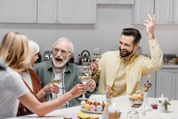 Homme excité geste avec la main levée près de la famille griller avec des verres à vin — Photo de stock