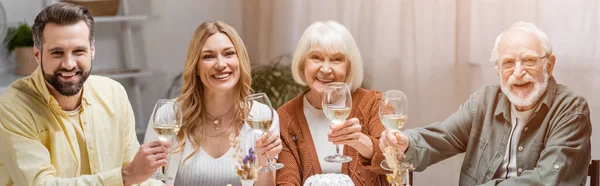 Freudige Familie blickt in die Kamera und hält Weingläser während der Osterfeier, Banner — Stockfoto