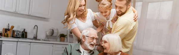 Ragazza eccitata divertirsi con i genitori vicino nonna e nonno a casa, banner — Foto stock