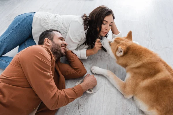Young woman and happy man lying of floor with akita inu dog — Stock Photo