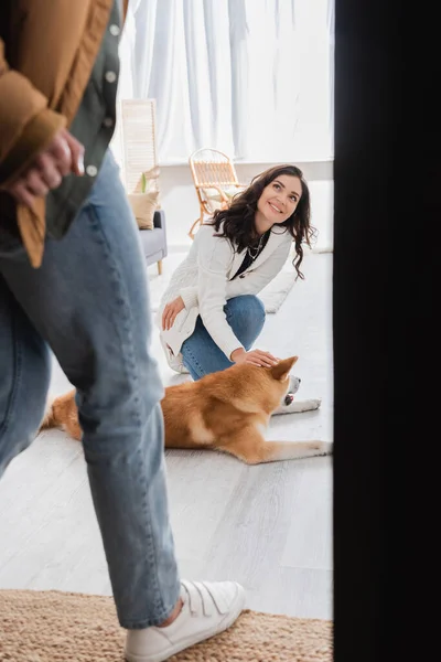 Happy woman cuddling akita inu dog and looking at blurred boyfriend — Stock Photo