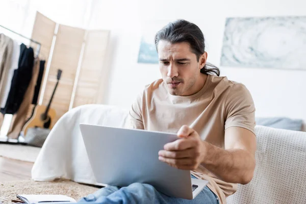 Libero professionista pensieroso che guarda il computer portatile in camera da letto — Foto stock