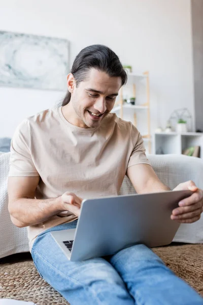 Cheerful freelancer looking at laptop in bedroom — Stock Photo