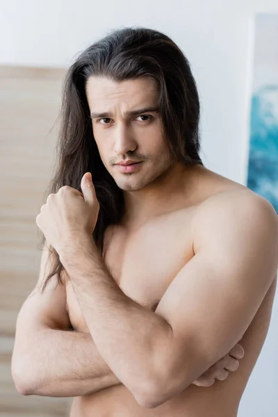 Ritratto di uomo senza maglietta con i capelli lunghi guardando la macchina fotografica — Foto stock