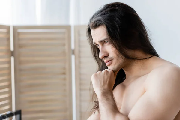 Задумчивый мужчина без рубашки с длинными волосами — стоковое фото