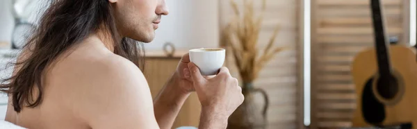 Vista recortada del hombre sin camisa con el pelo largo sosteniendo taza de café, pancarta - foto de stock