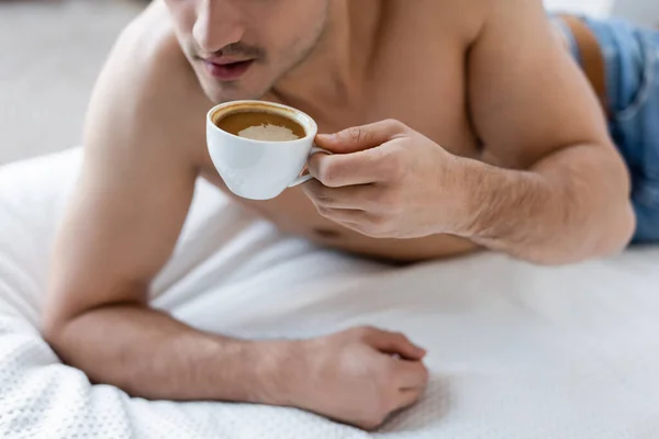 Partial view of shirtless man holding cup of coffee in bedroom — Stock Photo