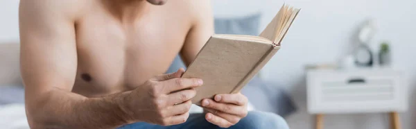 Vista recortada del hombre sin camisa que lee el libro en casa, bandera - foto de stock