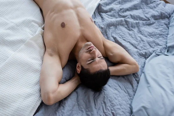 Vista dall'alto di uomo senza camicia sdraiato sul letto a casa — Foto stock