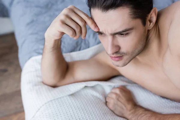 Blick von oben auf einen Mann ohne Hemd, der auf dem Bett liegt und wegschaut — Stockfoto