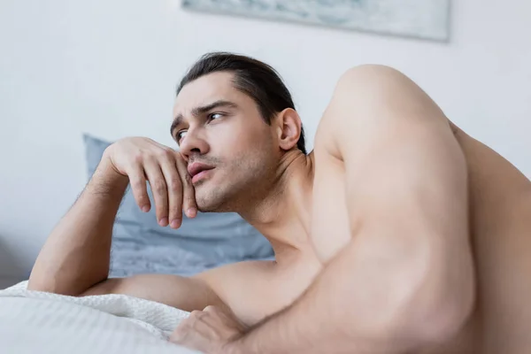 Hemdloser Mann ruht sich auf Bett aus und schaut weg — Stockfoto
