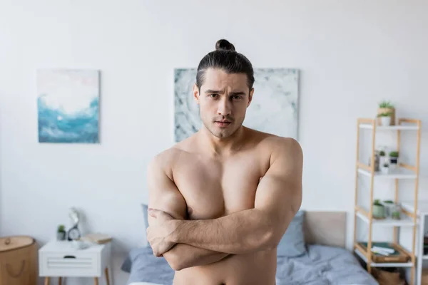 Uomo senza maglietta con i capelli lunghi in piedi con le braccia incrociate e guardando la fotocamera — Foto stock