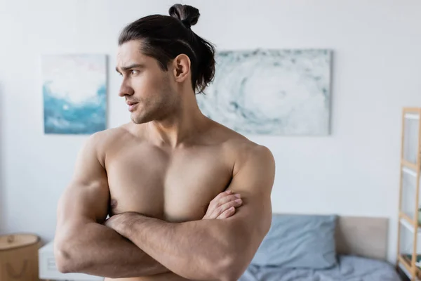 Muscular man with long hair standing with crossed arms and looking away — Stock Photo