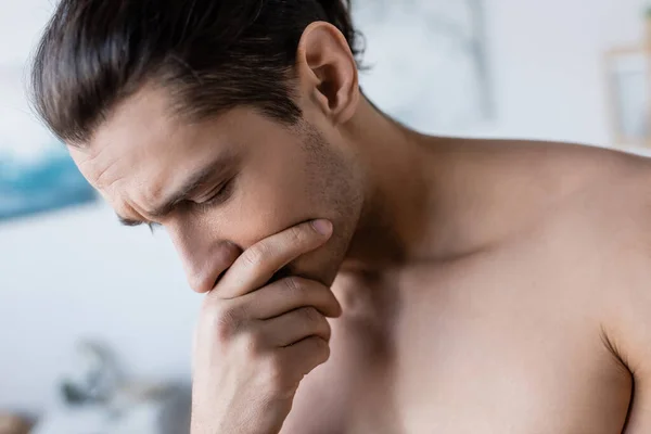 Close up of worried man covering mouth and looking down — Stock Photo