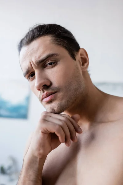 Hombre serio y sin camisa mirando a la cámara en casa - foto de stock