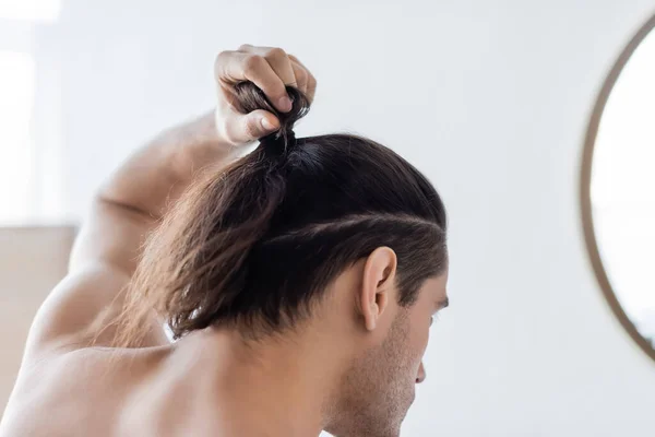 Vue arrière de l'homme coiffant les cheveux longs en chignon — Photo de stock