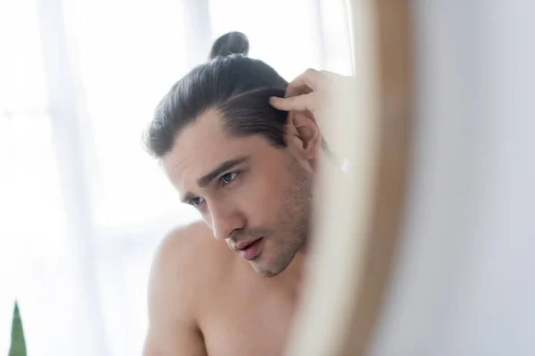 Homme torse nu avec un chignon de cheveux regardant miroir — Photo de stock