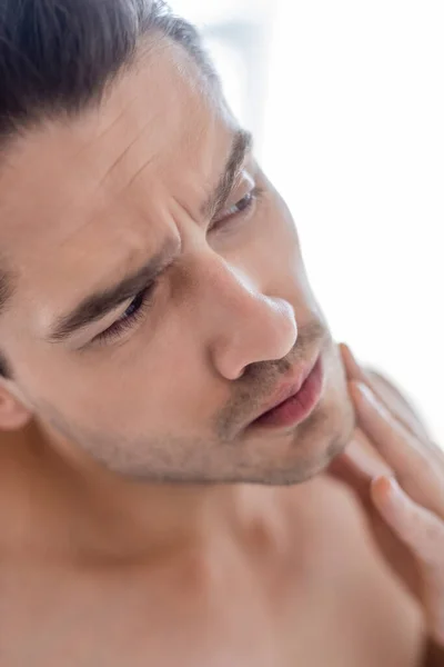 Close up view of man touching chin in bathroom — Stock Photo