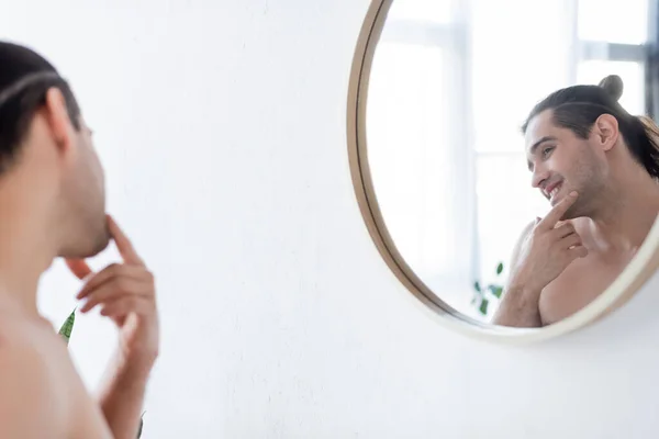 Homem alegre e sem camisa sorrindo enquanto olha para o espelho no banheiro — Fotografia de Stock
