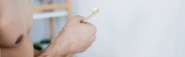 Частковий вид людини, що тримає зубну щітку з зубною пастою у ванній кімнаті, банер — Stock Photo