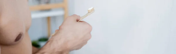 Partial view of man holding toothbrush with toothpaste in bathroom, banner — Stock Photo