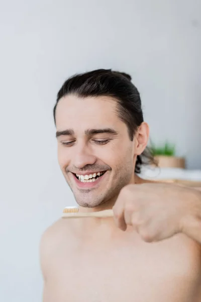 Homem alegre segurando escova de dentes com pasta de dentes no banheiro — Fotografia de Stock