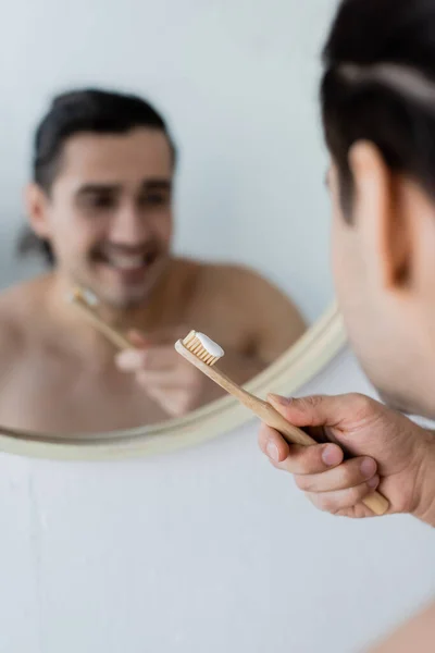 Homem desfocado e alegre segurando escova de dentes com pasta de dentes no banheiro — Fotografia de Stock