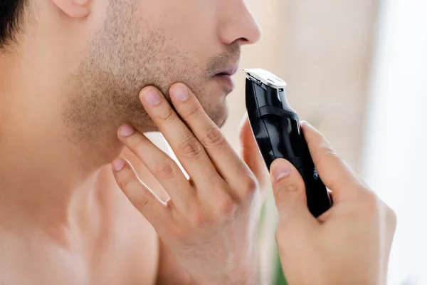 Cropped view of man shaving with electric razor — Stock Photo