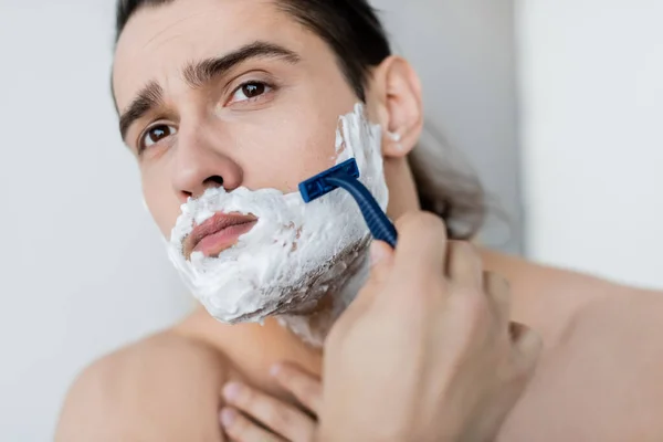 Homem sem camisa com espuma no rosto de barbear no banheiro — Fotografia de Stock