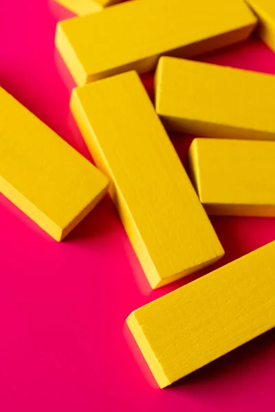 Close up of yellow quadrangular blocks on pink background, top view — Stock Photo
