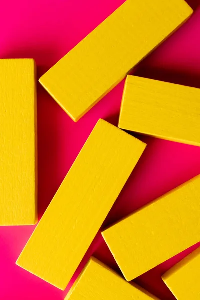 Primer plano de bloques de color amarillo brillante sobre fondo rosa, vista superior - foto de stock