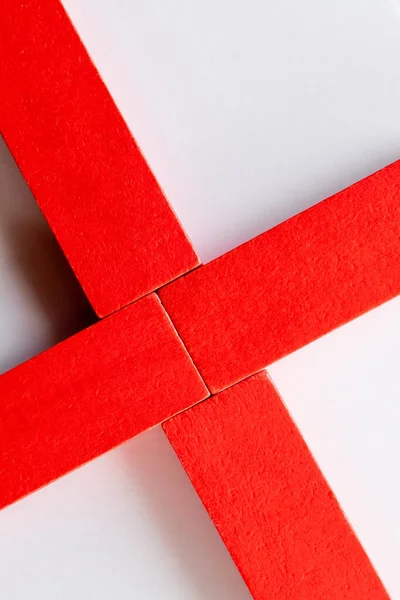Крупним планом хрест з червоних блоків на білому тлі, вид зверху — стокове фото