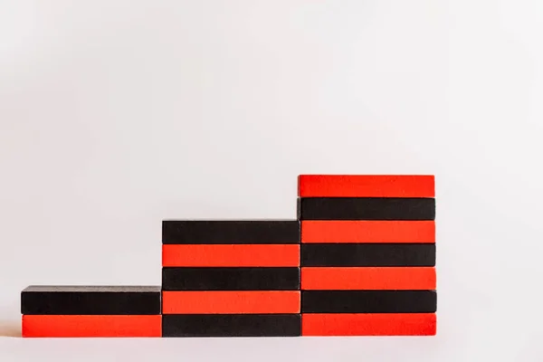 Bloques rojos y negros apilados en forma de escaleras sobre fondo blanco - foto de stock