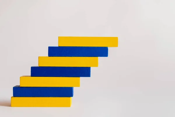 Bloques azules y amarillos apilados sobre fondo blanco, concepto ucraniano - foto de stock