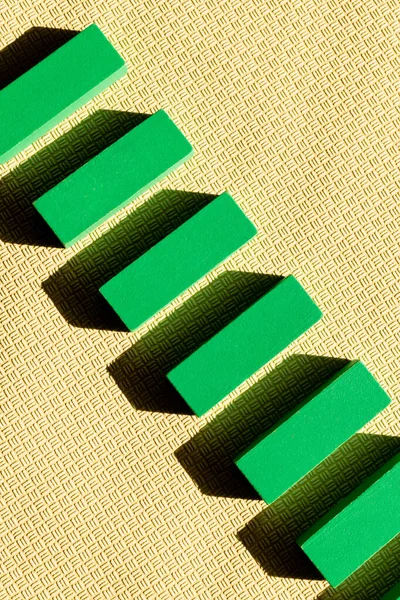 Vista superior de la fila diagonal de bloques verdes sobre fondo texturizado beige - foto de stock