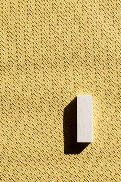 Vista superior de bloque rectangular blanco sobre fondo beige texturizado con espacio de copia - foto de stock