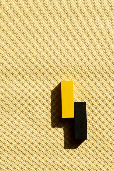 Верхний вид черных и желтых блоков на бежевом текстурированном фоне с копированием пространства — стоковое фото
