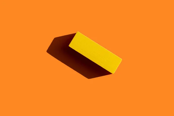 Top view of colored yellow block on orange background with shadow — Stock Photo