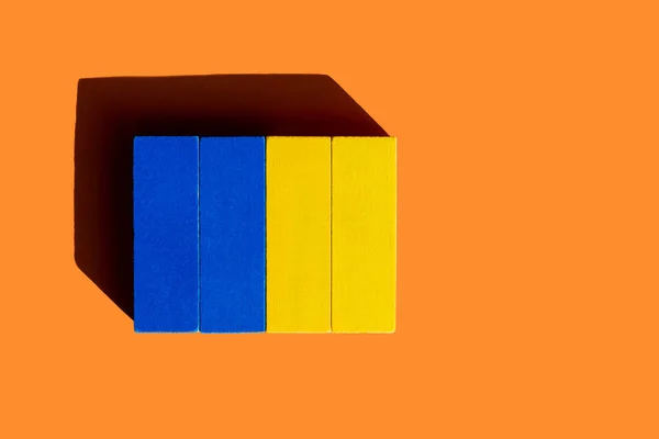 Top view of colorful blue and yellow blocks on orange background, ukrainian concept — Stock Photo