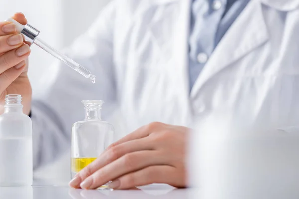 Cropped view of laboratory assistant holding serum with pipette — Stock Photo