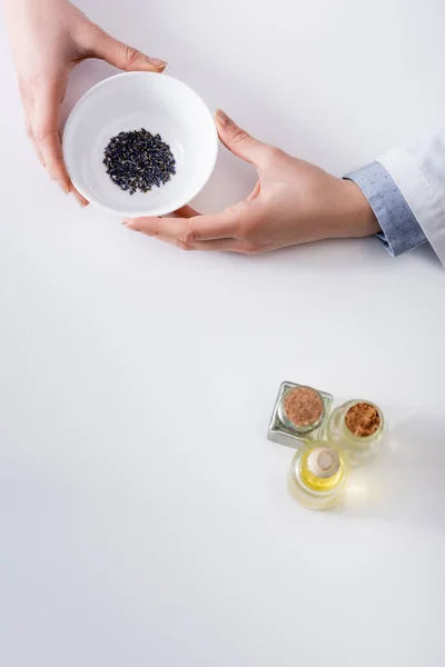 Top view of woman holding bowl with dried lavender while making cosmetics — Stock Photo