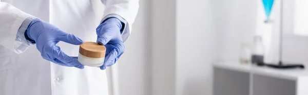 Vista cortada de químico em luvas de látex segurando recipiente com creme, banner — Fotografia de Stock