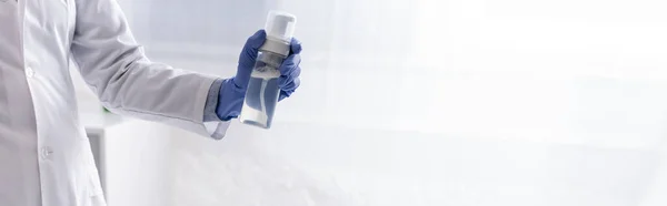 Vue partielle de l'assistant de laboratoire dans une bouteille à gants en latex avec produit cosmétique, bannière — Photo de stock