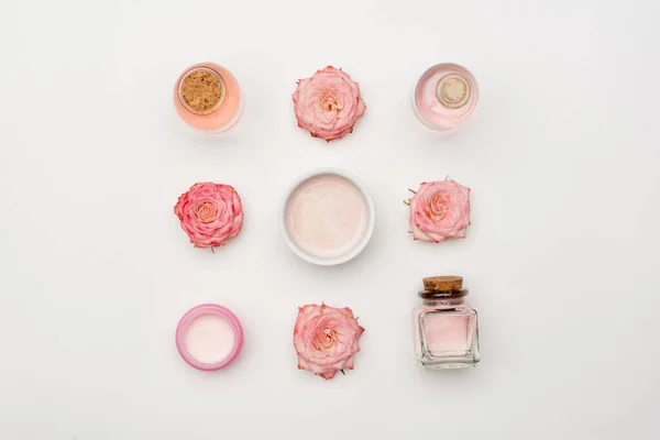 Vista superior de flores perto de creme e garrafas com produtos cosméticos em branco — Fotografia de Stock