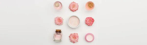 Colocação plana de flores perto de creme e garrafas com produtos cosméticos em branco, banner — Fotografia de Stock