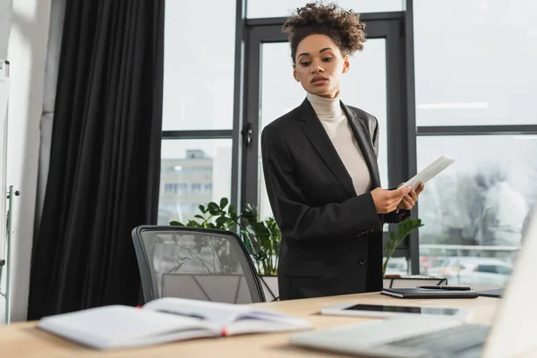 Donna d'affari afroamericana con tablet digitale vicino al tavolo da lavoro in ufficio — Foto stock